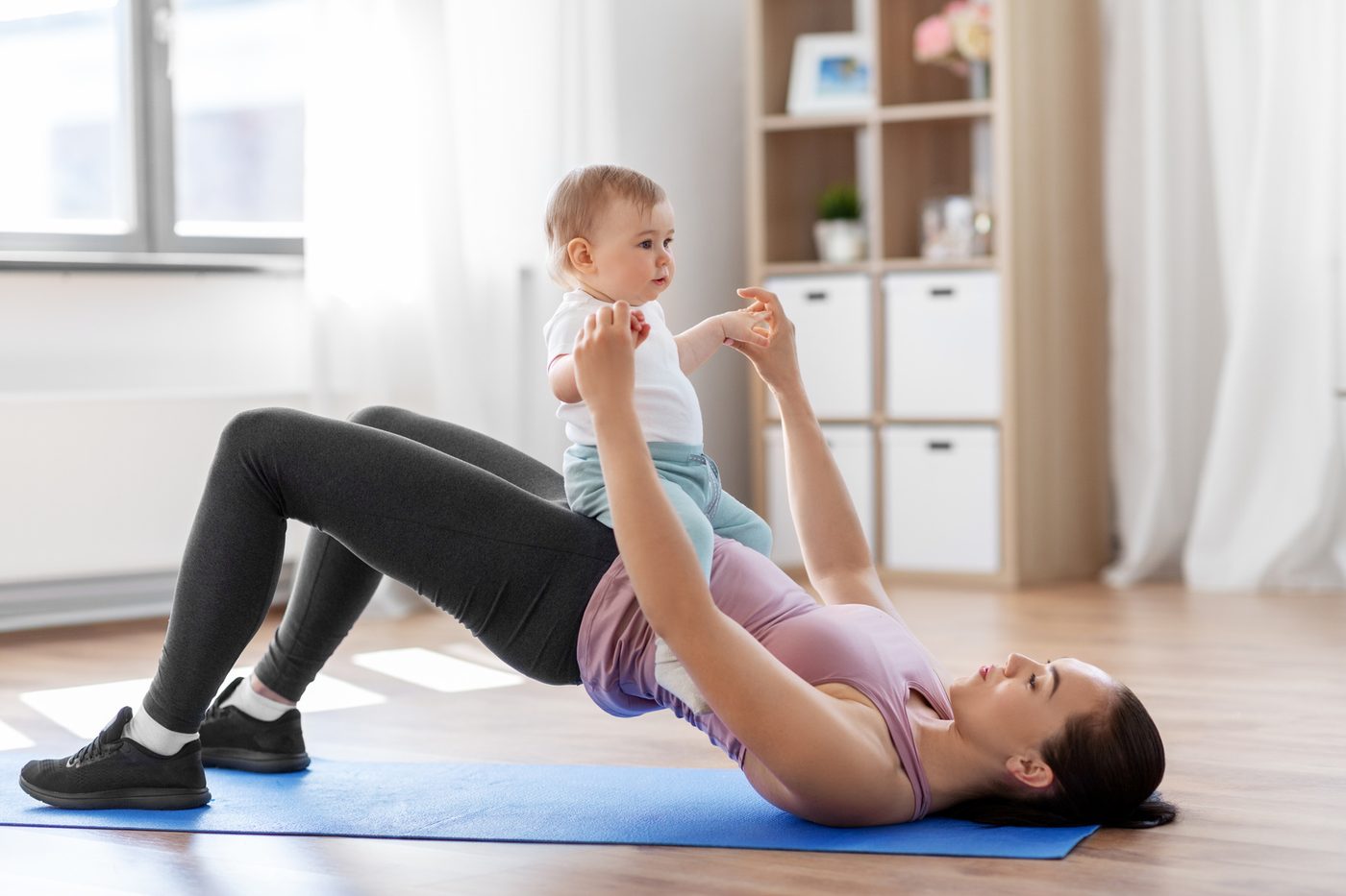 A mother doing a guided postpartum strength exercise with her baby